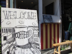 Welcome Coffee Sign with Cafe in distance Woodberry Coffee Roasters in Yoga Tokyo Japan